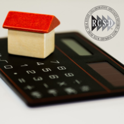 A small house sits on top of a calculator.